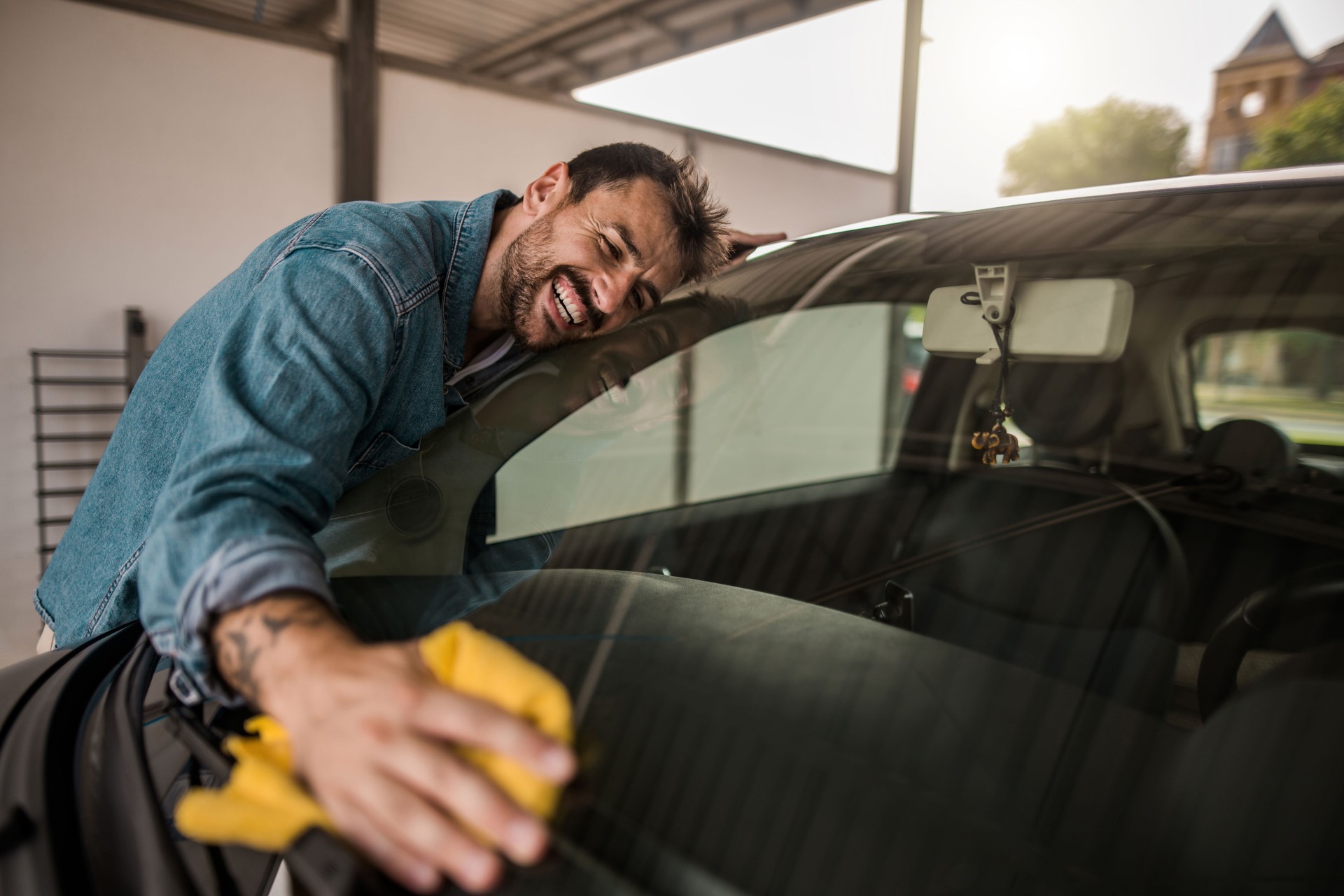 Young man embracing his car at outdoor car wash.